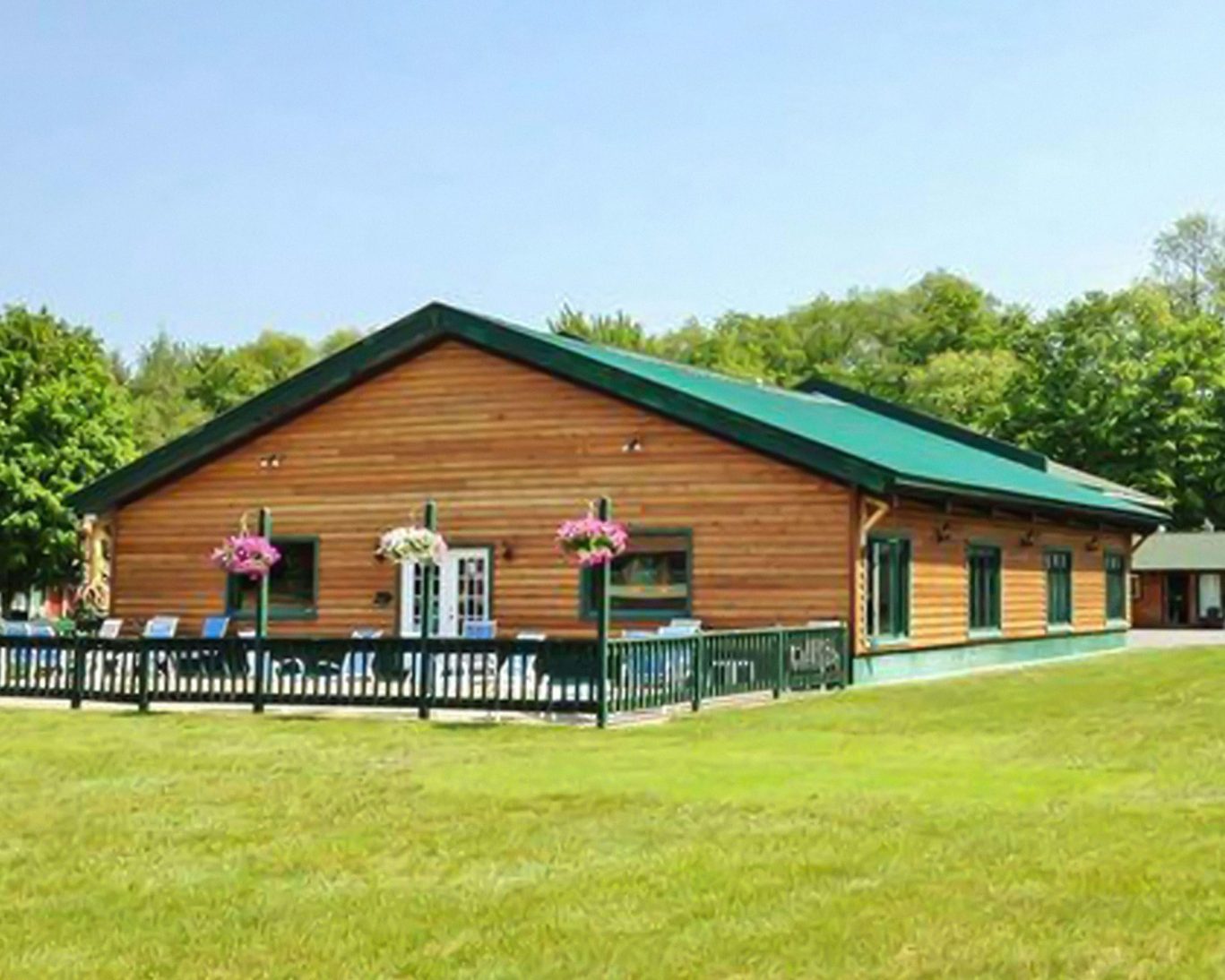 Scenic lodge-style hotel building with green roof and flower-adorned patio in summer.