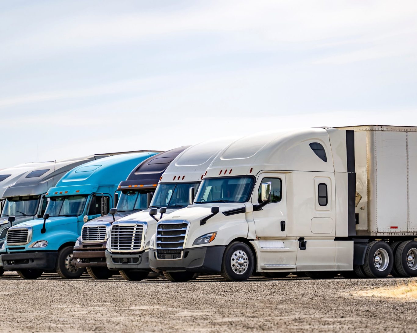 Row of parked semi-trucks at a motel with large vehicle parking accommodations.