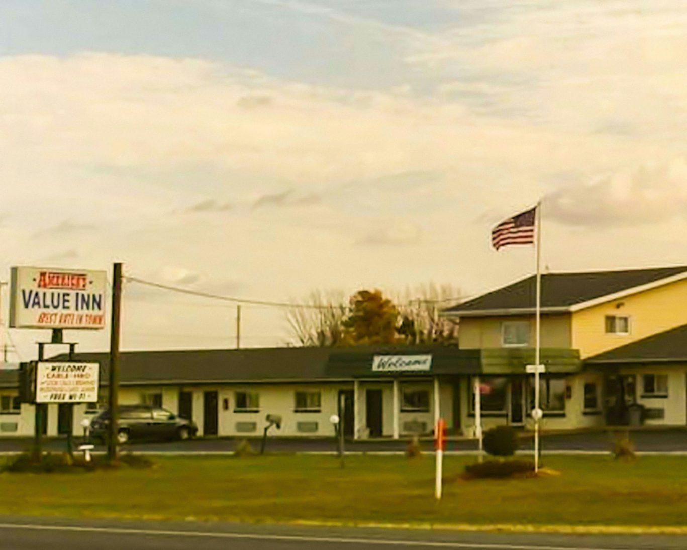 Exterior of Ashland Value Inn motel with American flag and roadside sign offering free Wi-Fi and cable TV.