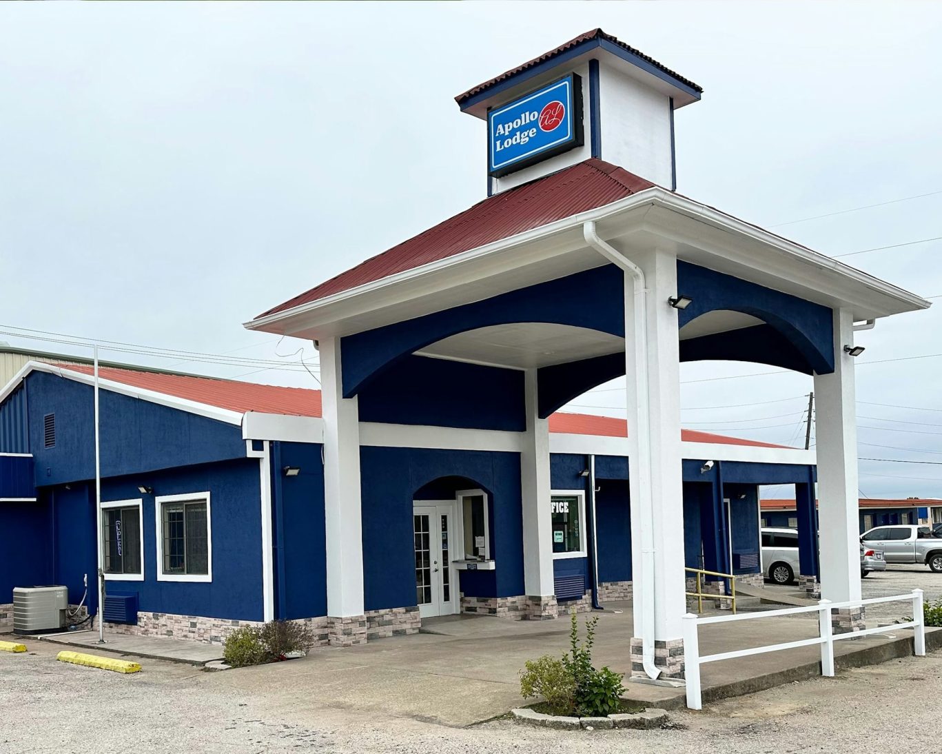 Front entrance of Apollo Lodge motel with covered drive-through and red roof.