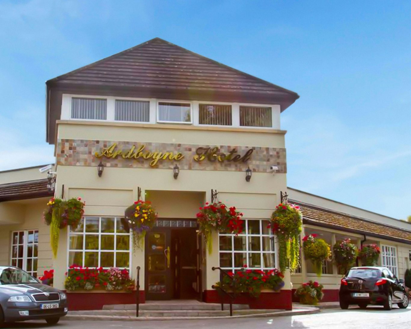 Front entrance of Ardboyne Hotel with hanging flower baskets and guest parking.