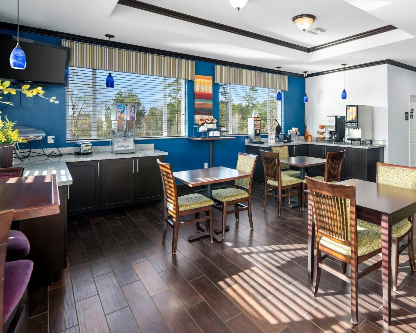 Bright breakfast dining area with modern decor and self-serve beverage stations at Belmont Inn & Suites.