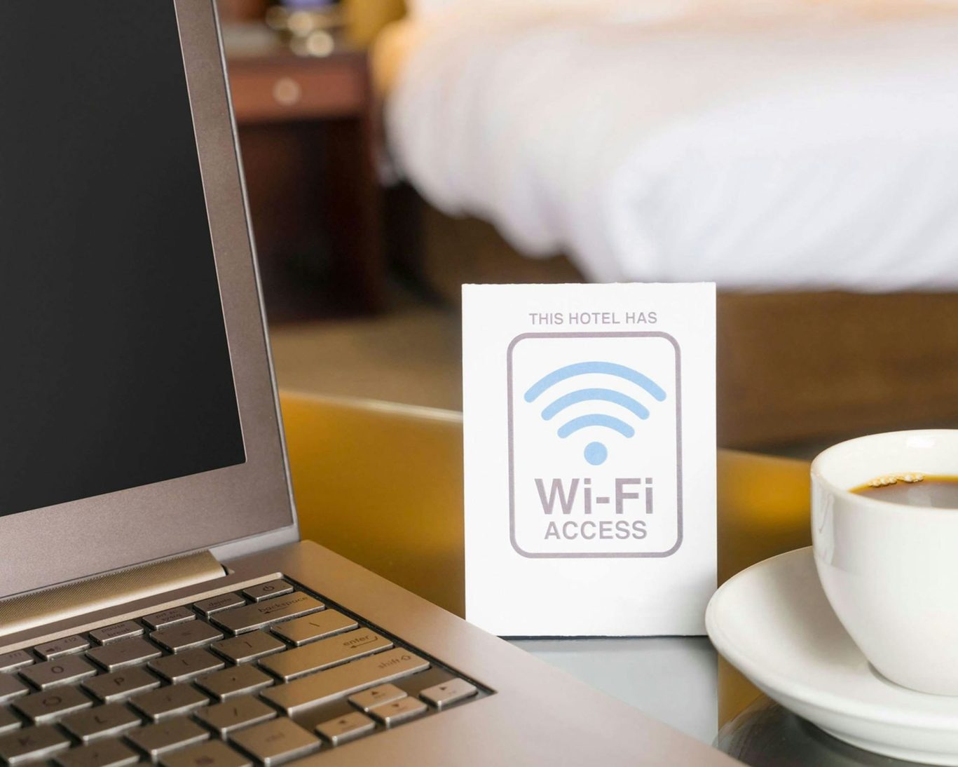 Hotel Wi-Fi access sign beside laptop and coffee cup in guest room at Belmont Inn & Suites.