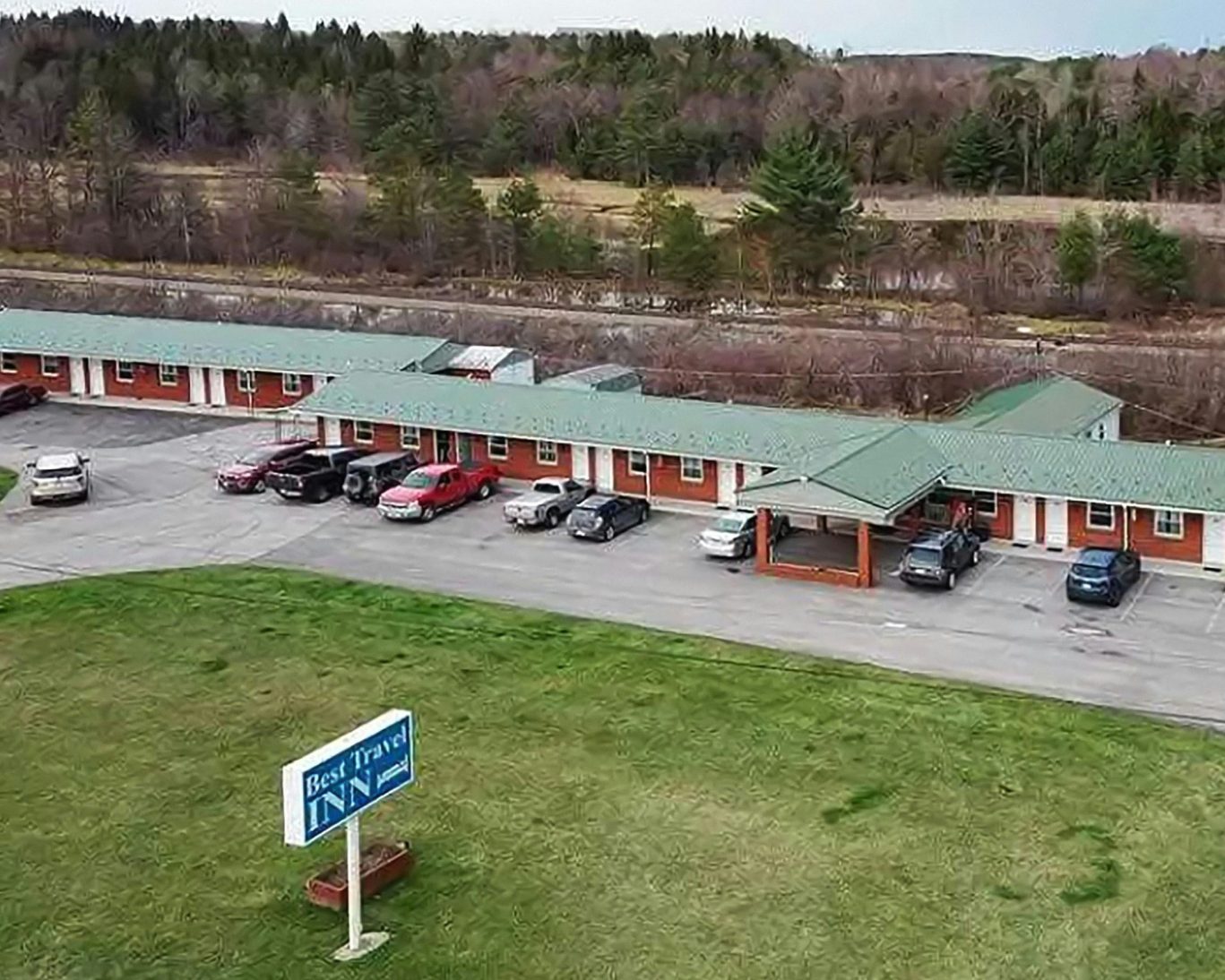 Aerial view of Best Travel Inn with guest parking and forest backdrop.
