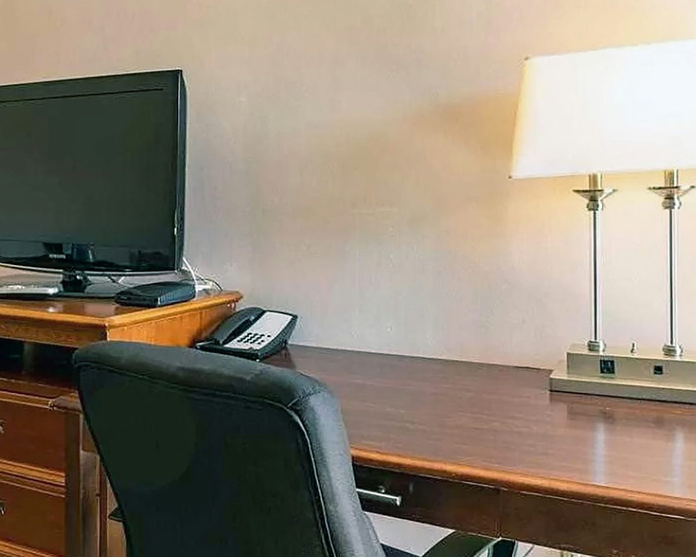In-room workspace with desk, flat-screen TV, and lamp at Best Travel Inn.