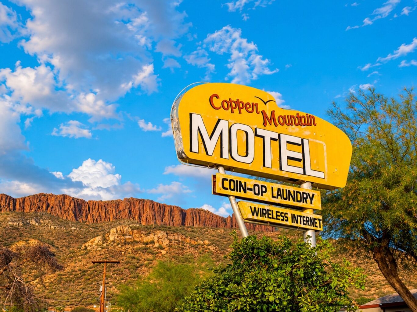 Vintage Copper Mountain Motel sign with mountain backdrop in Arizona desert.