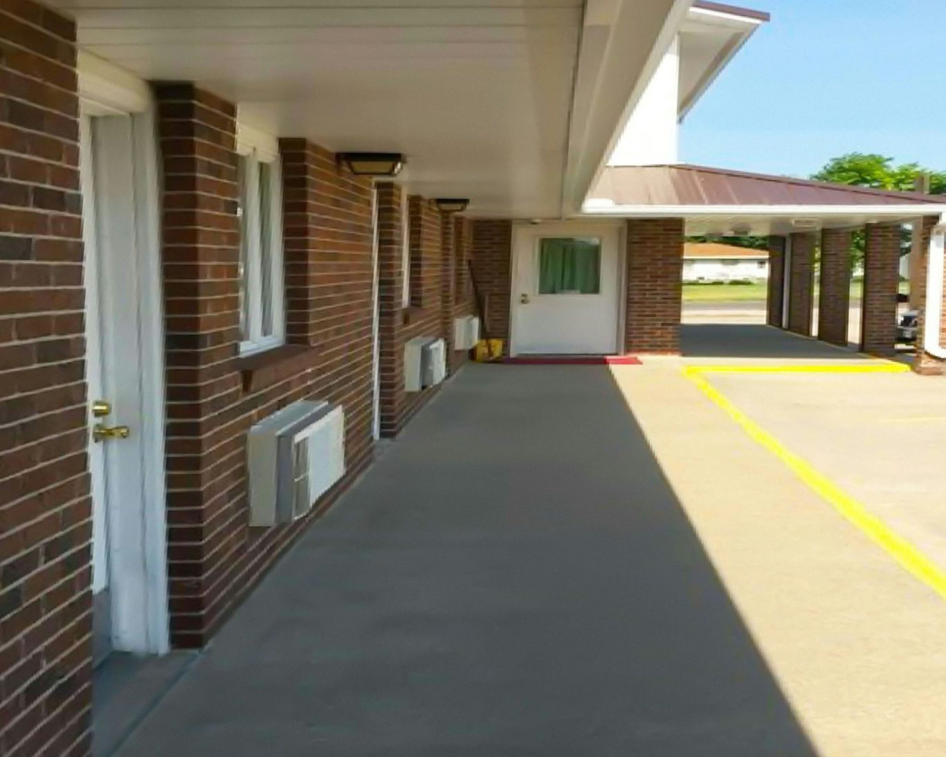 Covered walkway and guest room entrances at Drop Tyne Lodge with brick walls.