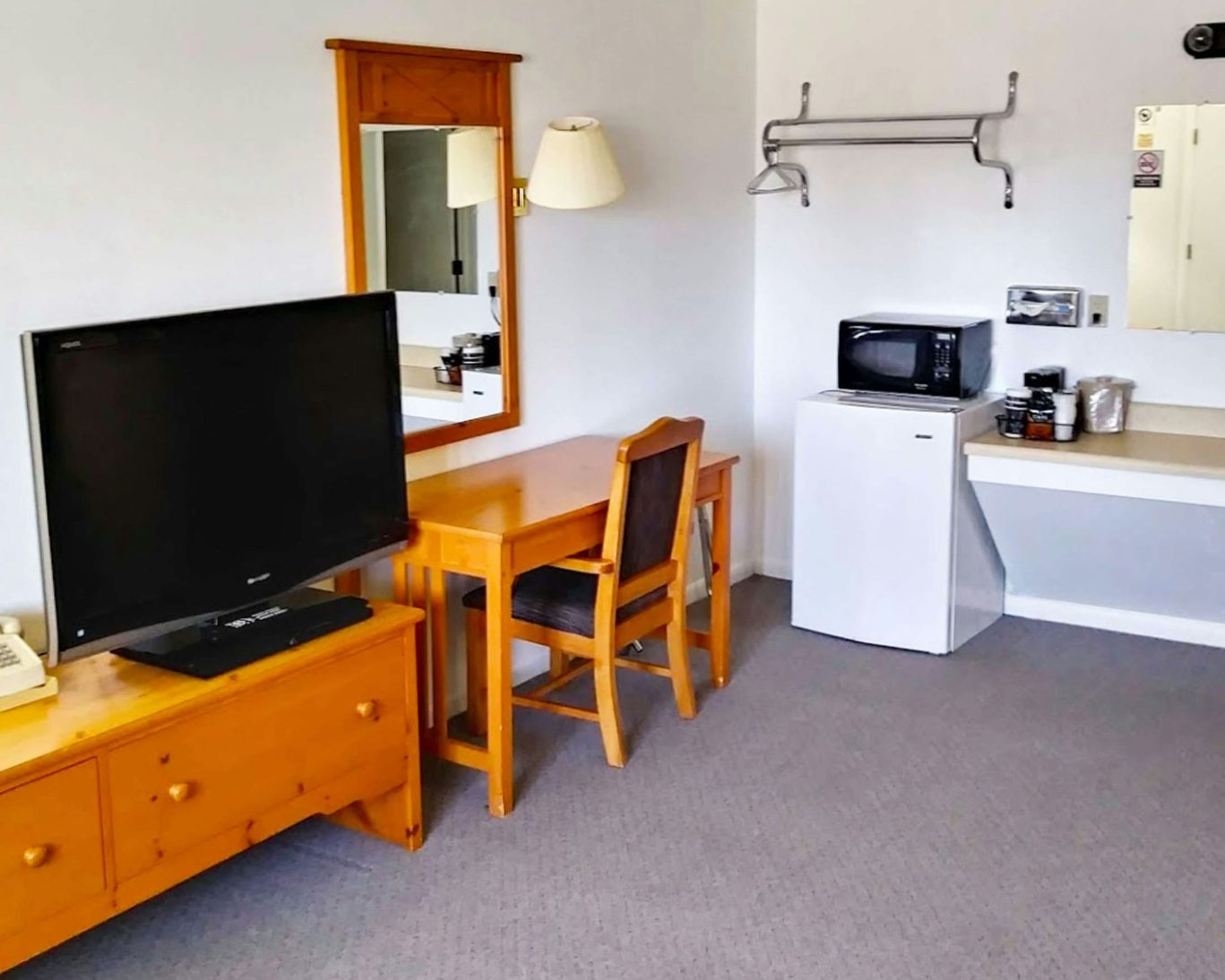 Guest room interior at Drop Tyne Lodge with TV, desk, microwave, and mini fridge.