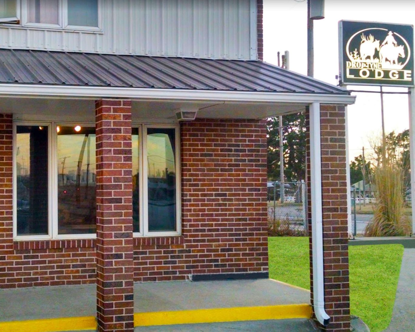 Exterior of Drop Tyne Lodge with brick façade and illuminated lodge sign at dusk.