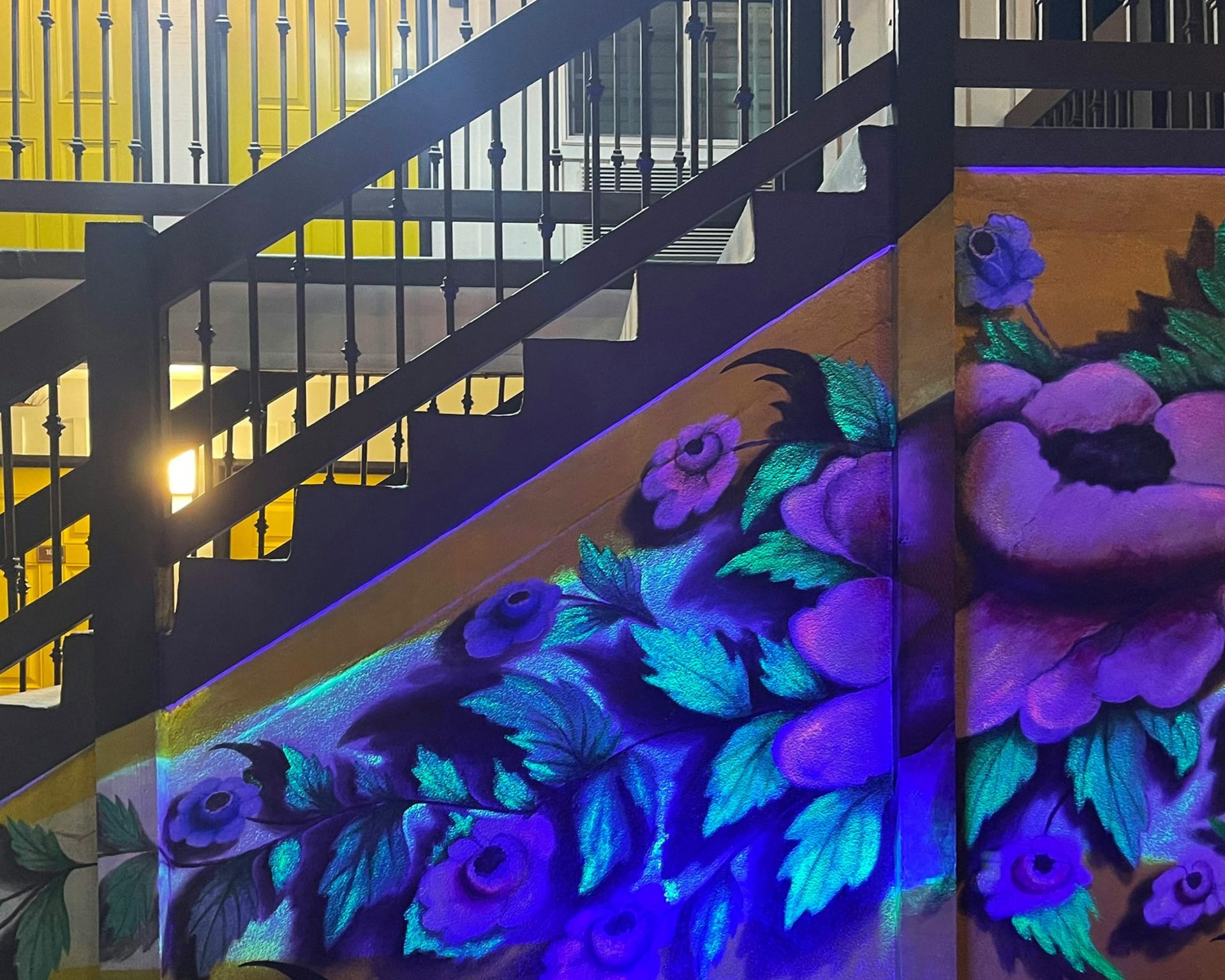 Colorful floral mural under staircase at Escondida Motel, showcasing unique artistic decor.