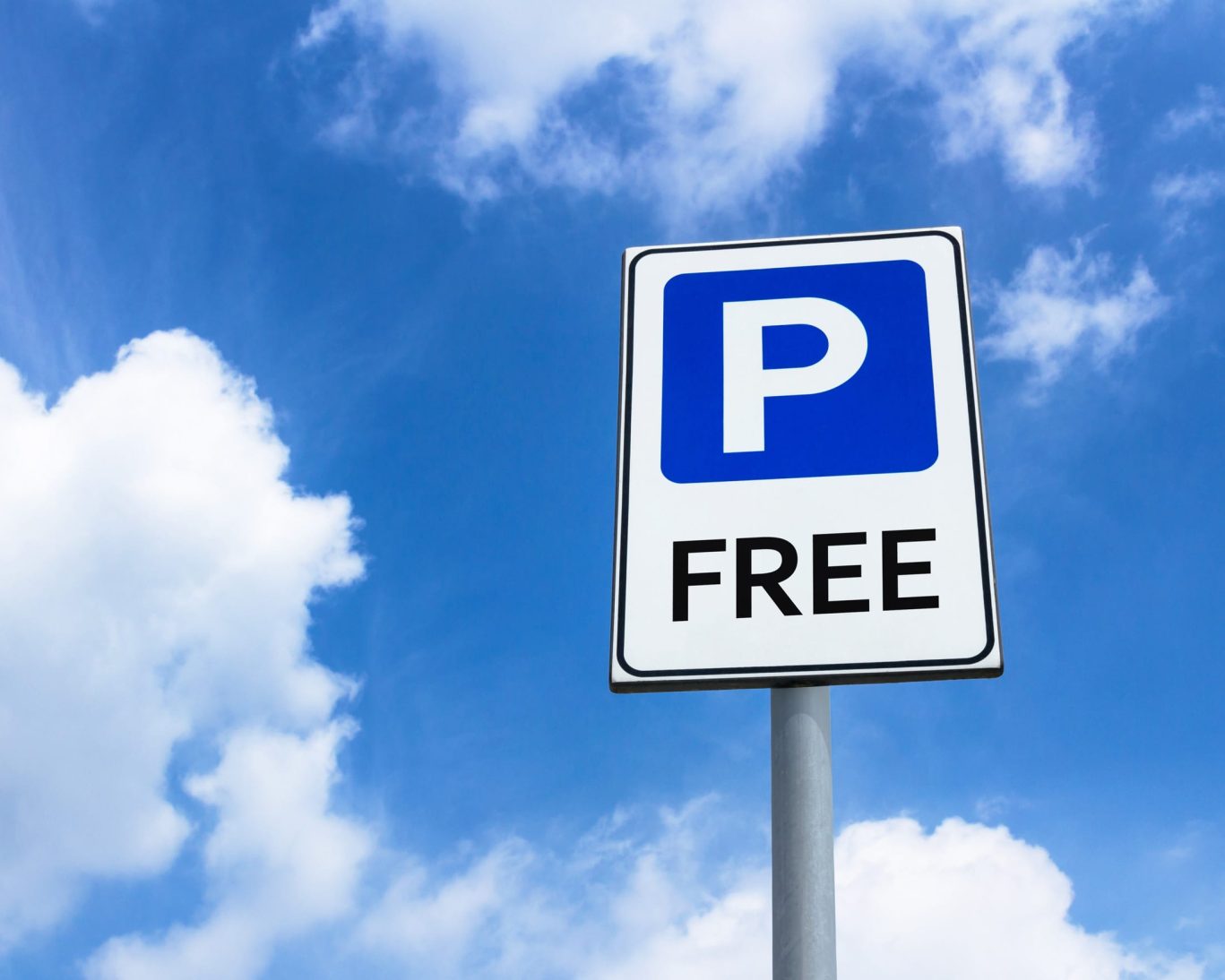 Free guest parking available at Escondida Motel, marked with clear signage under a blue sky.