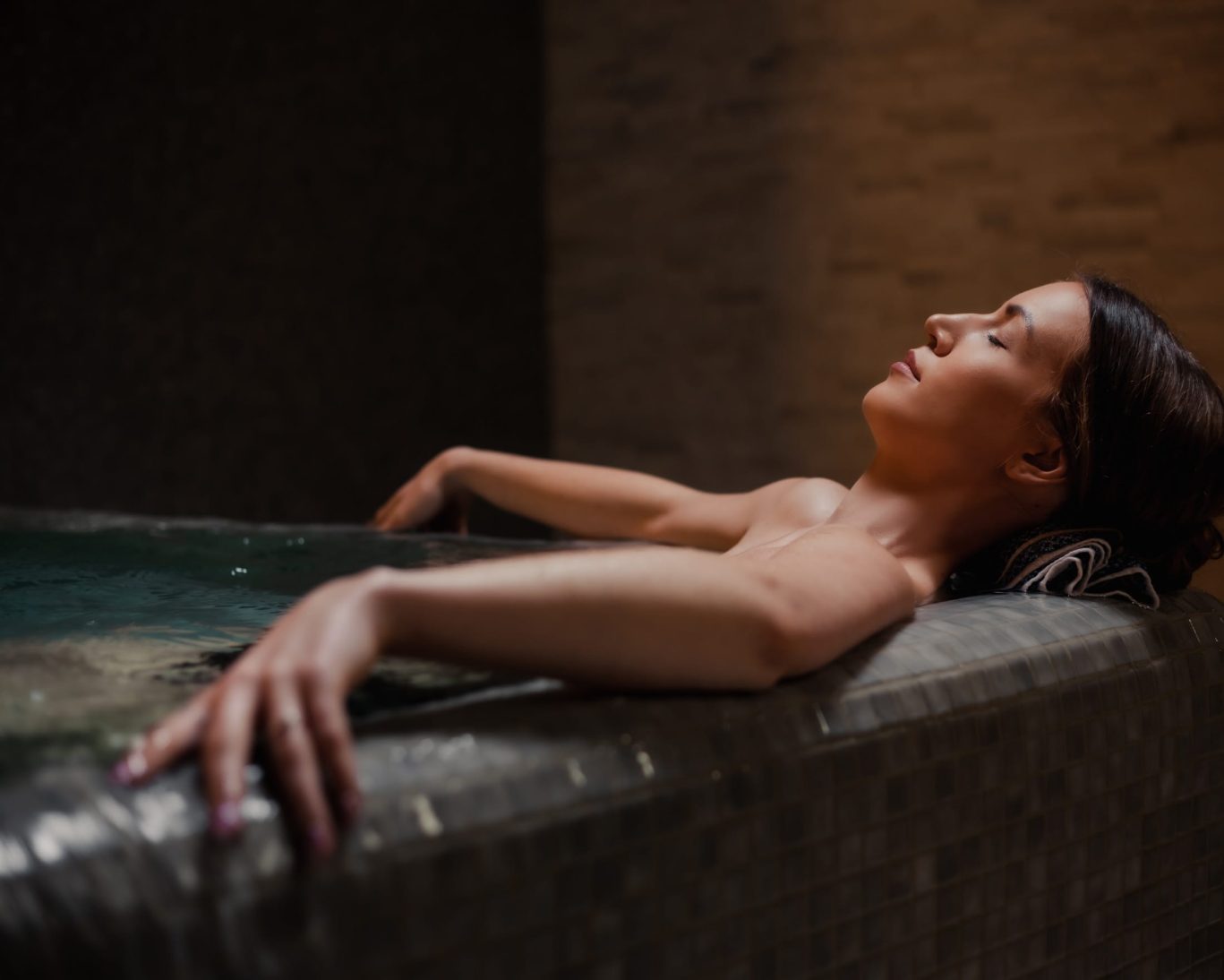 Woman relaxing in a warm spa bath at Georgetown Lodge wellness facility.