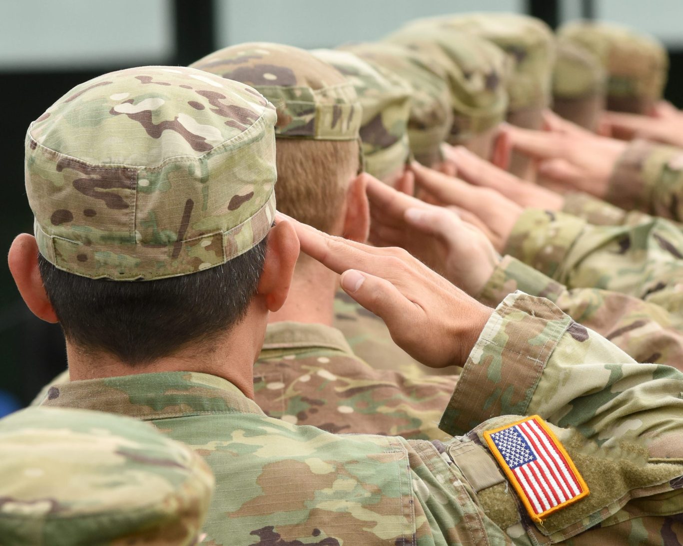 U.S. Army soldiers saluting with American flag patch, representing proximity to Fort Riley near Golden Wheat Motel.