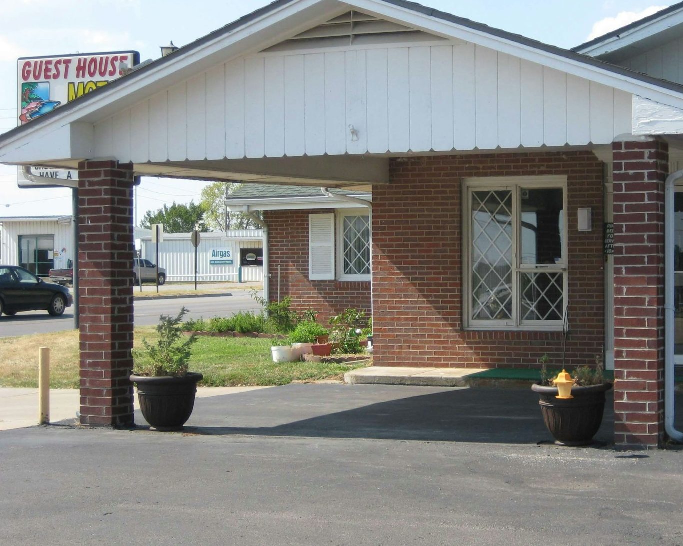 Front entrance of Guest House Motel in Chanute, Kansas with brick facade and driveway.