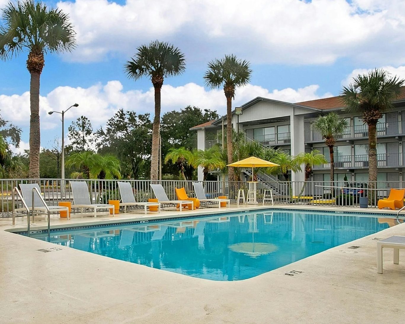 Outdoor swimming pool with palm trees and lounge chairs at H1 Extended Stay Kissimmee.