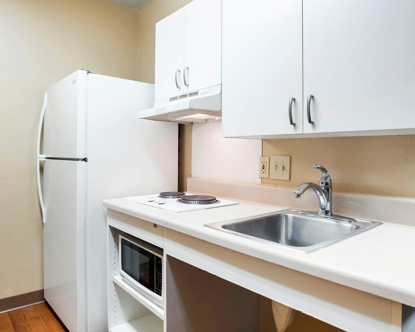 Compact kitchen with fridge, stove, and microwave at H1 Suites Montgomery.