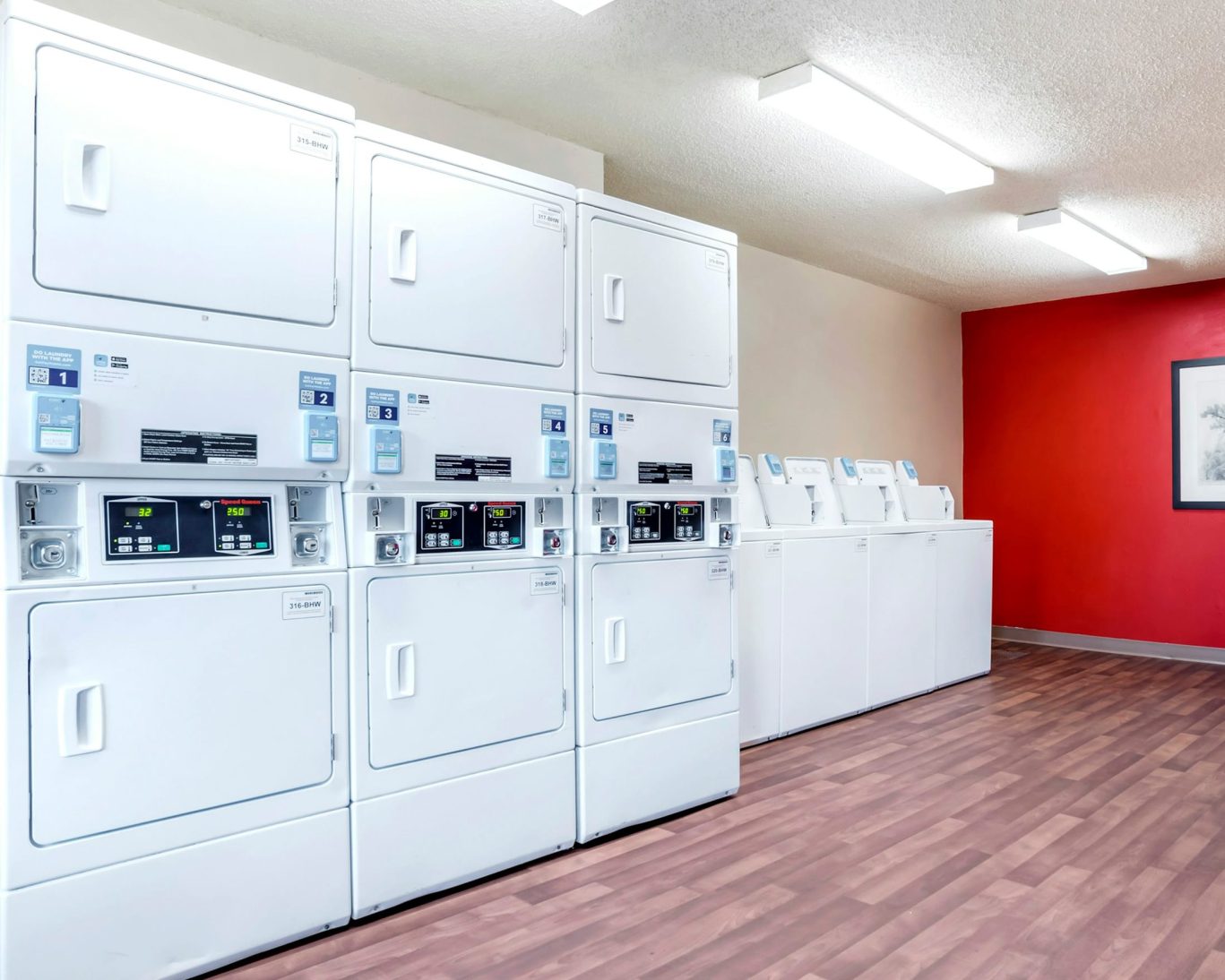 Laundry room with stacked washers and dryers at H1 Suites Montgomery.