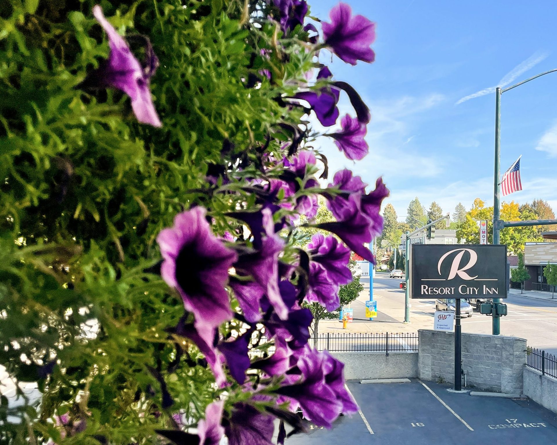 Exterior sign and parking area of Resort City Inn in downtown Coeur d'Alene with American flag visible.