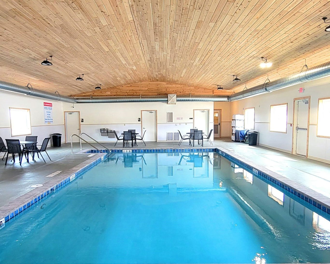 Spacious indoor swimming pool at Jasper Ridge Inn with wooden ceiling and poolside seating.