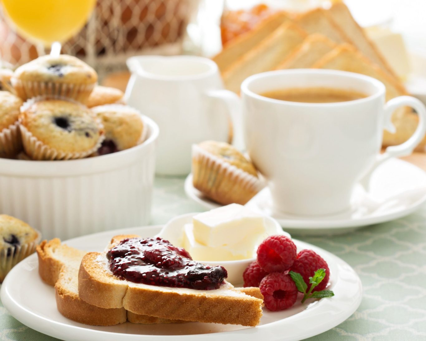 Continental breakfast at Jasper Ridge Inn featuring toast with jam, muffins, coffee, orange juice, and fresh raspberries.