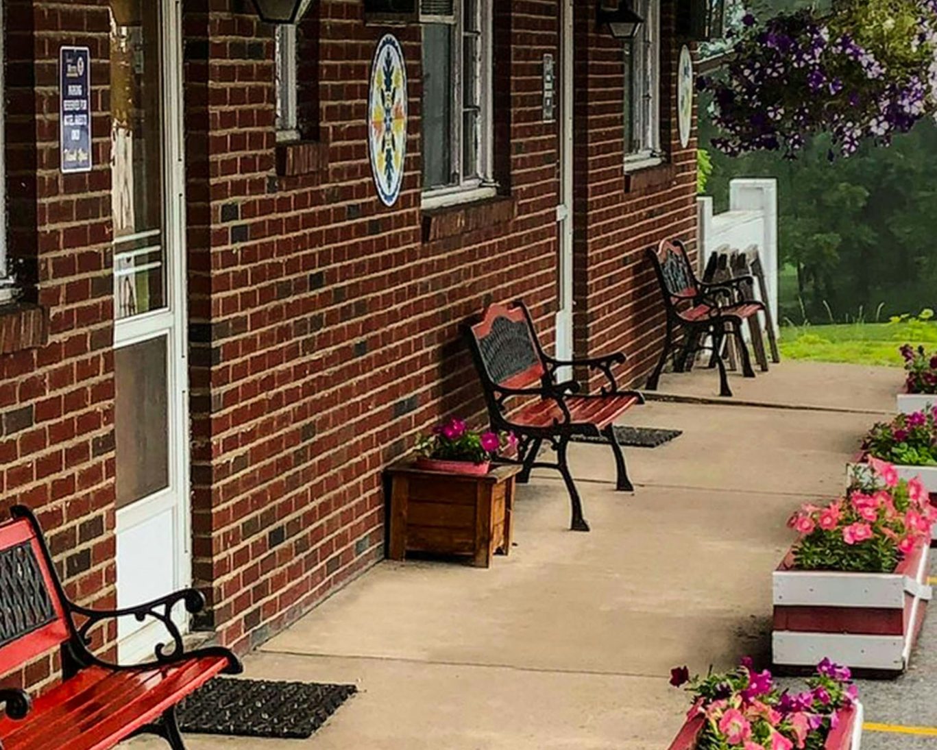 Brick exterior of Judy's Motel Bedford PA with outdoor benches and colorful flower planters.