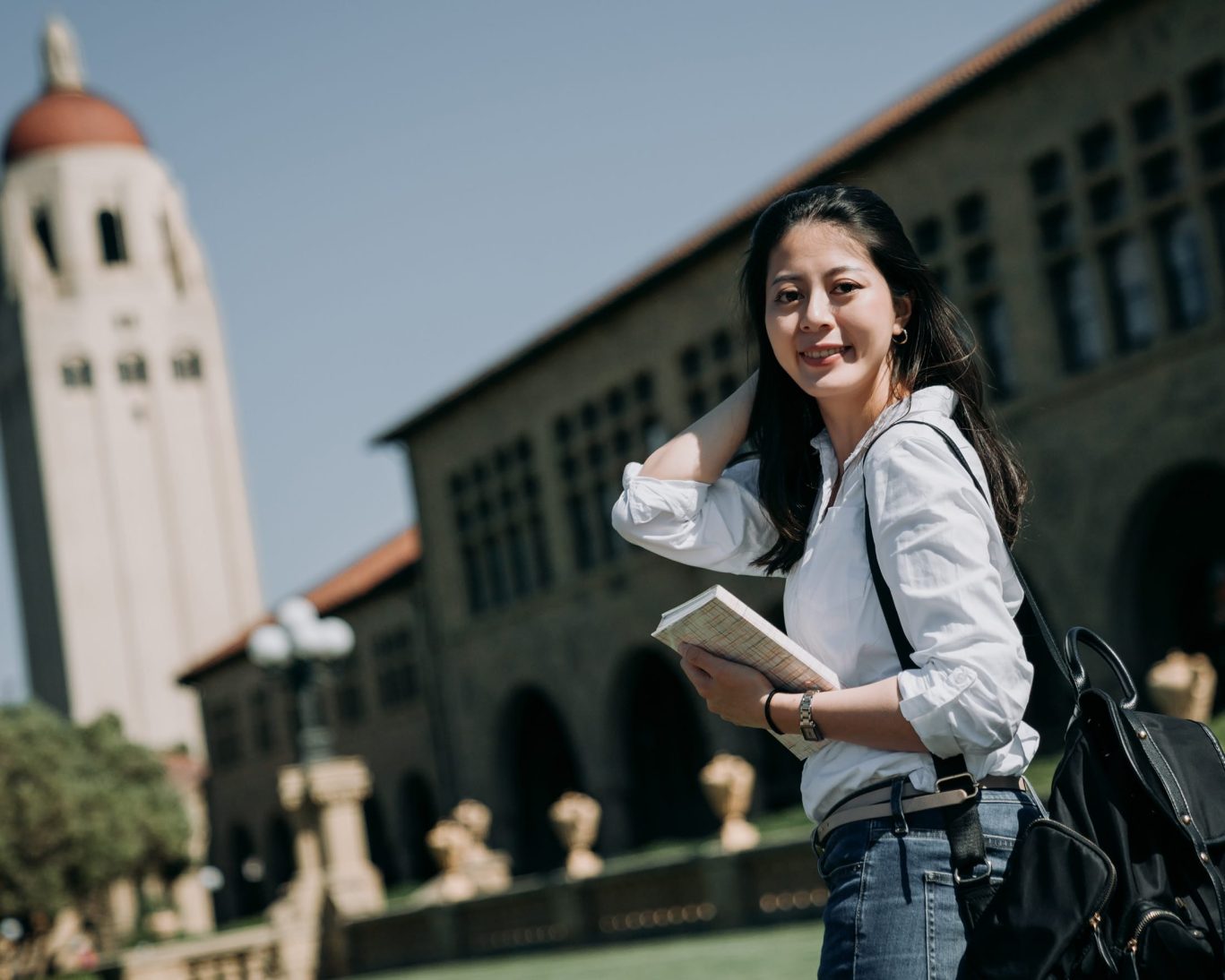 Female student smiling outside California State University campus holding books.