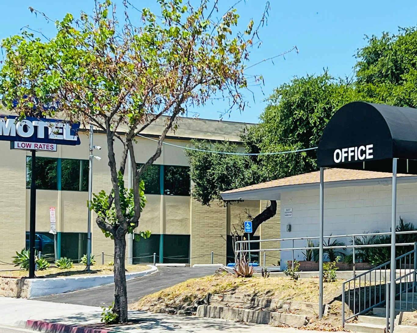Exterior view of budget-friendly Lanai Motel with office entrance and shaded sign.