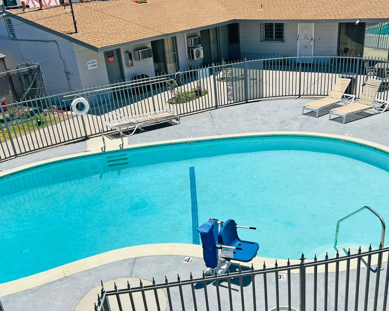 Accessible outdoor swimming pool at Lanai Motel with sun loungers and safety railing.