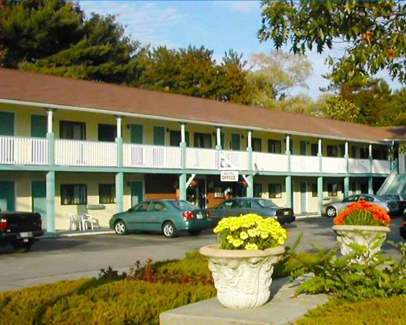 Exterior photo of Hampton Inn-style motel with two stories and colorful flower pots in the foreground.