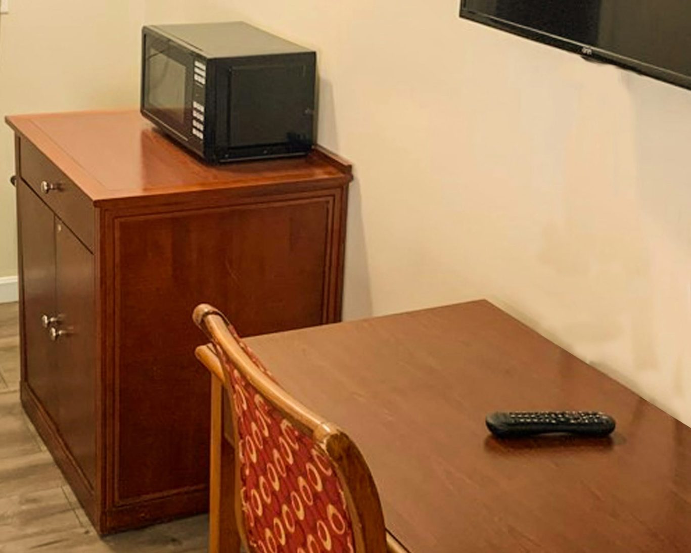 Guest room corner with microwave on cabinet, flat-screen TV, and wooden desk at Hampton motel.