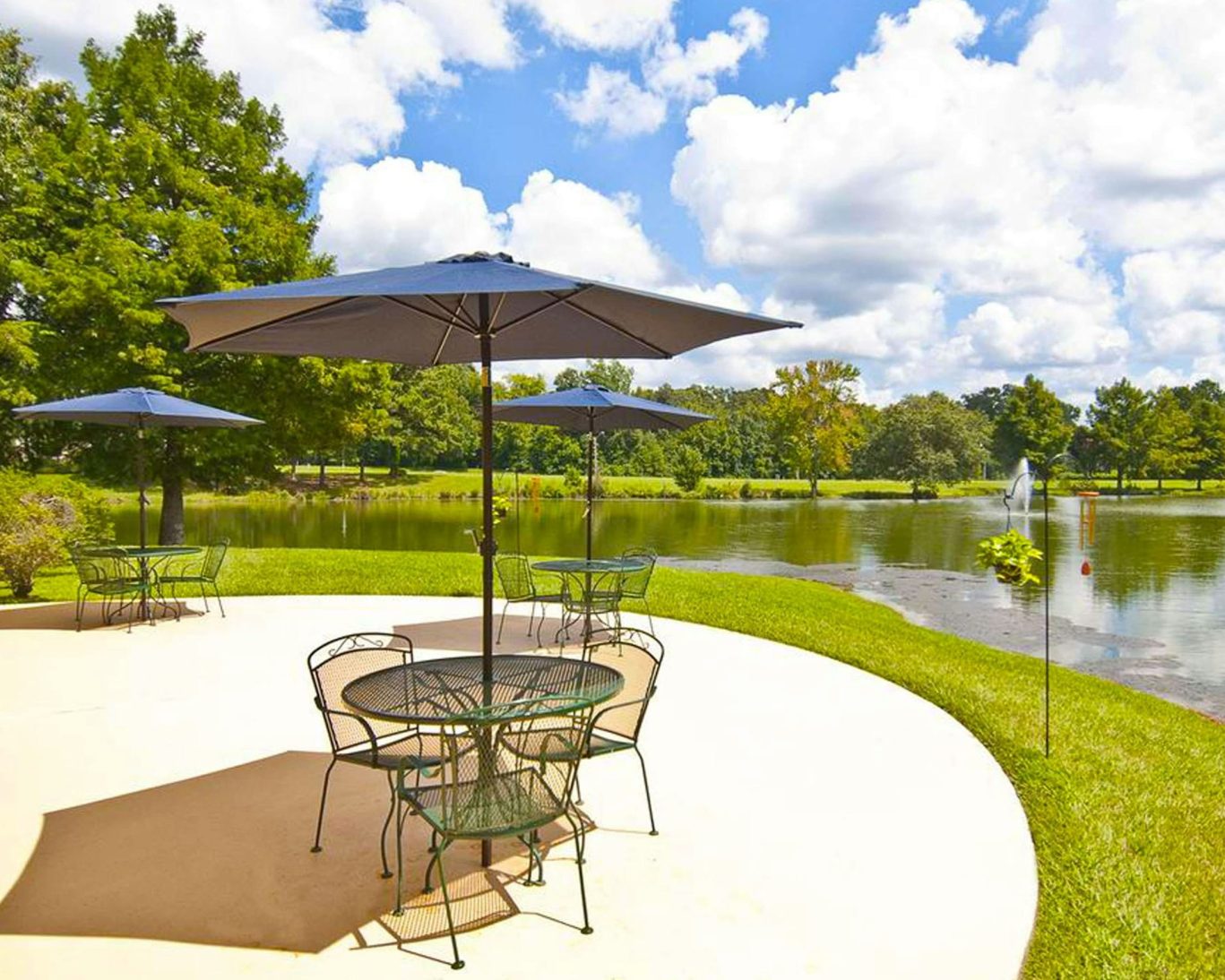 Outdoor patio with umbrellas and seating overlooking the lake at The Hotel Francis in Tatum, TX.