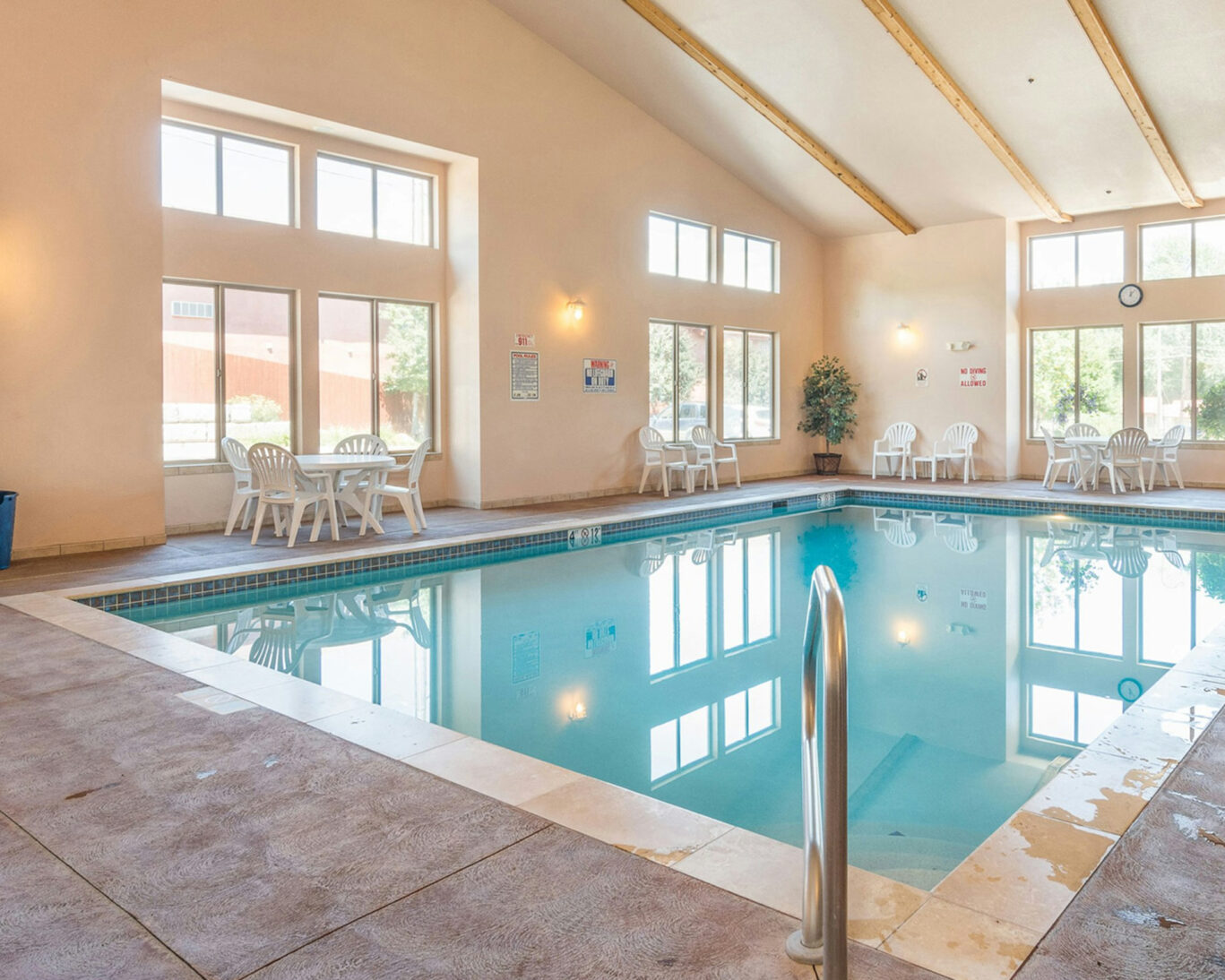 Indoor heated swimming pool at Manitou Springs hotel with natural lighting and seating area.