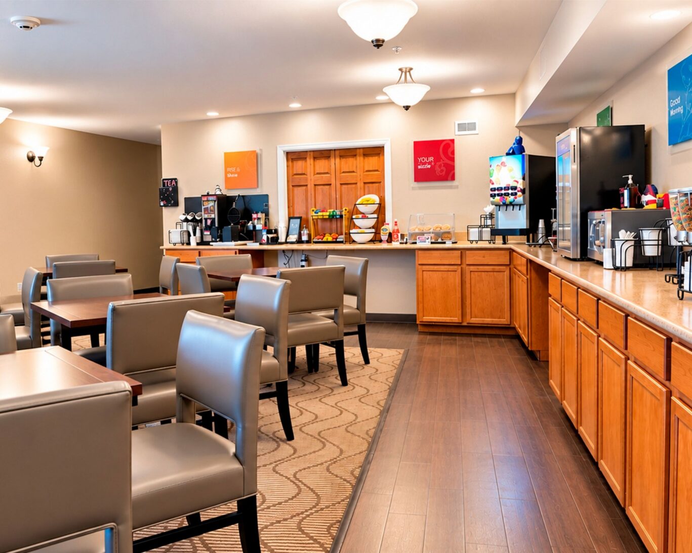 Breakfast area at Manitou Pikes Peak Hotel with dining tables, a serving counter, and coffee and waffle stations.