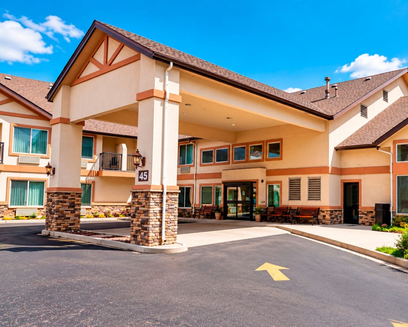 Covered main entrance at Manitou Pikes Peak Hotel with stone columns, sliding doors, and bench seating.