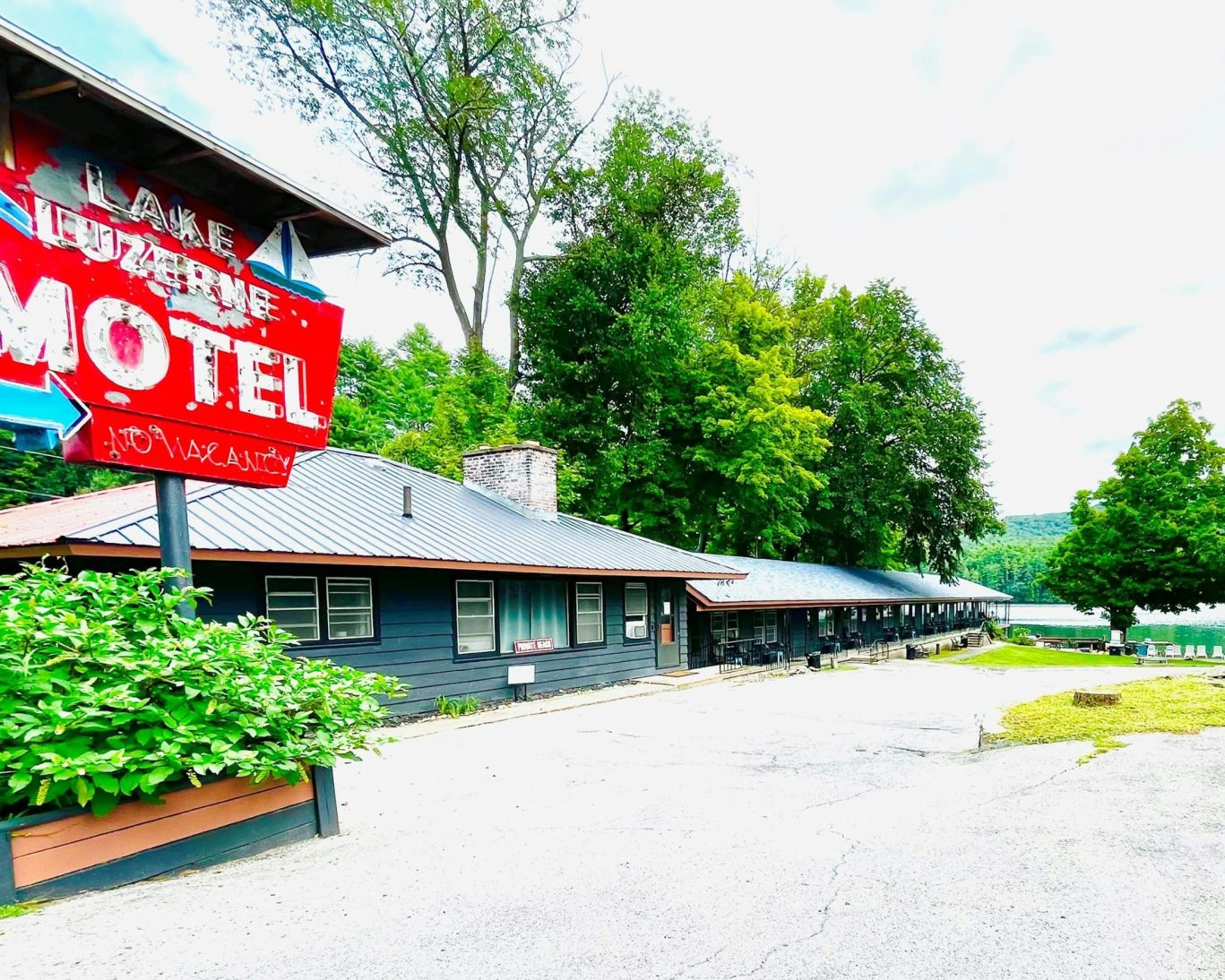 Exterior of Lake Luzerne Motel with vintage sign and scenic lakeside backdrop.