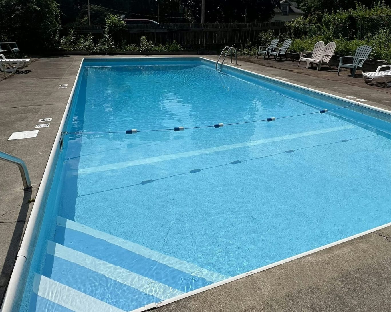 Outdoor swimming pool surrounded by lounge chairs at Lake Luzerne Motel.