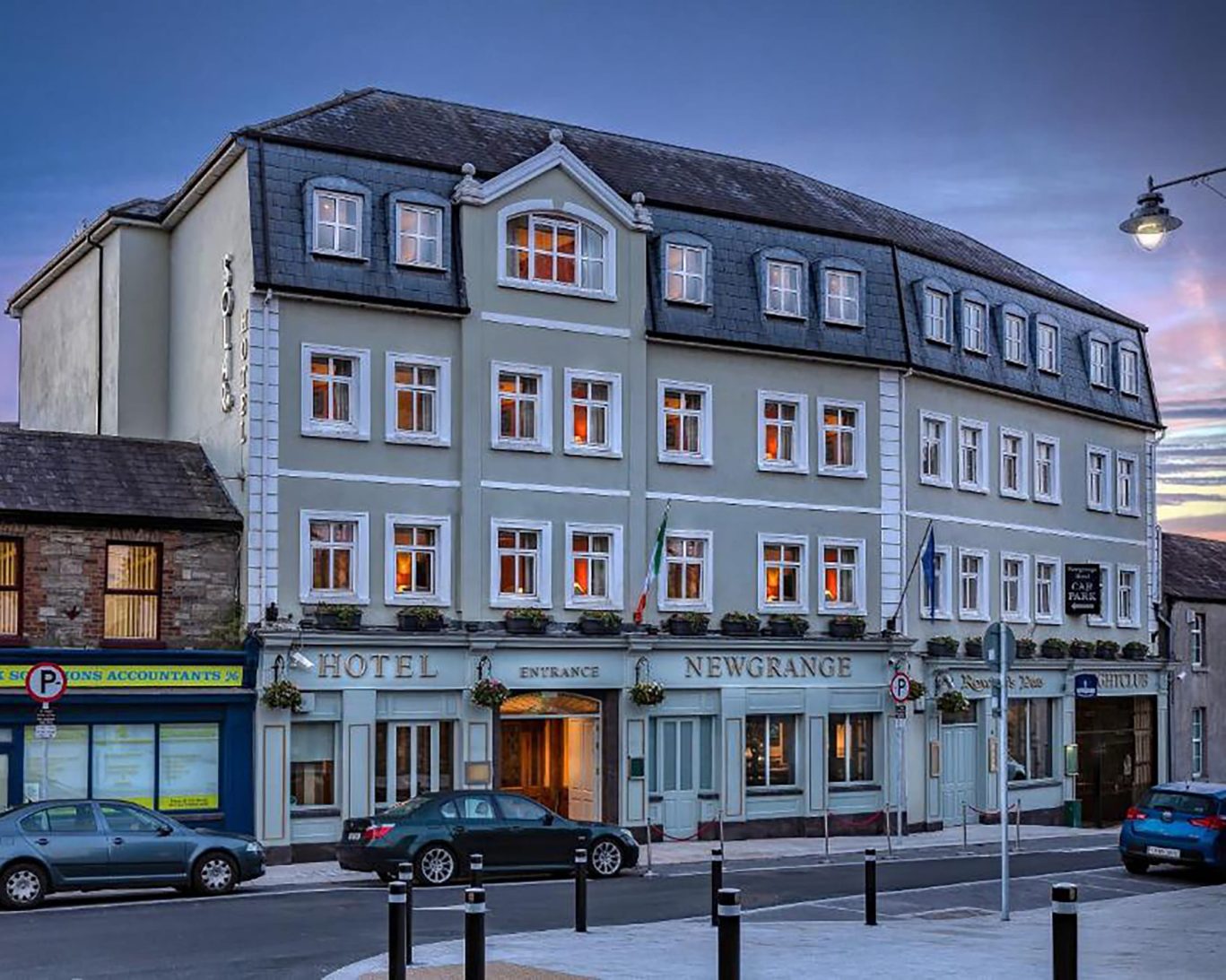 Elegant Georgian-style facade of The Newgrange Hotel Navan at dusk with warm lighting and street view.