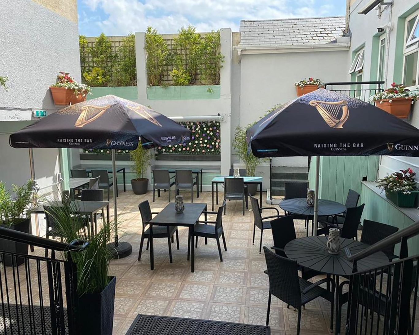 Courtyard seating at The Newgrange Hotel Navan with Guinness-branded umbrellas and potted plants.