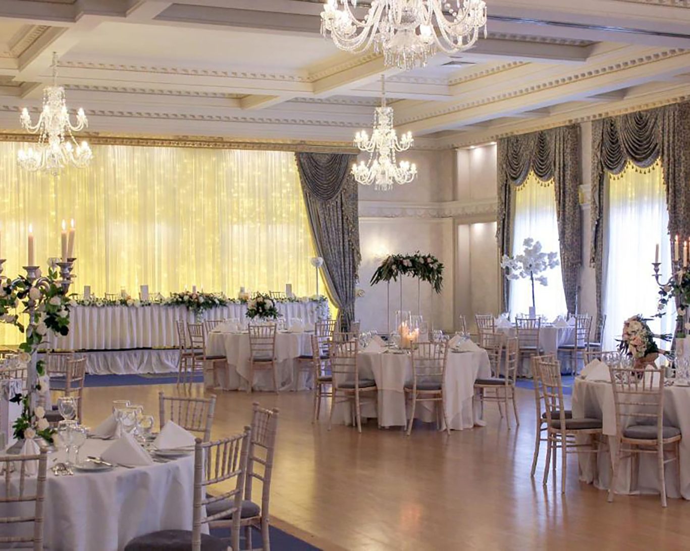 Luxurious ballroom at The Newgrange Hotel Navan with crystal chandeliers, banquet tables, and floral decor.