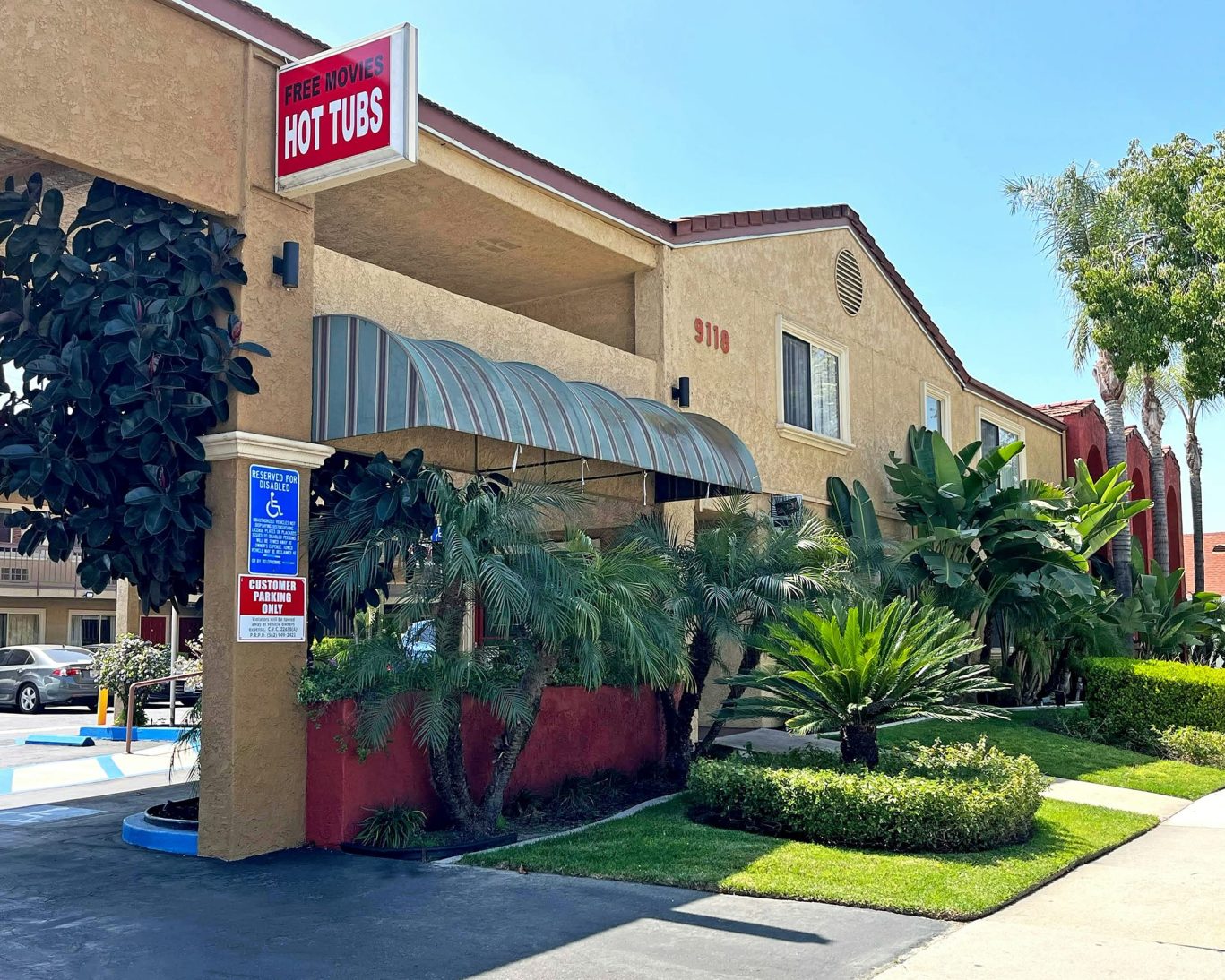 Front exterior of Rivera Inn & Suites Motel with tropical landscaping and hot tubs sign.