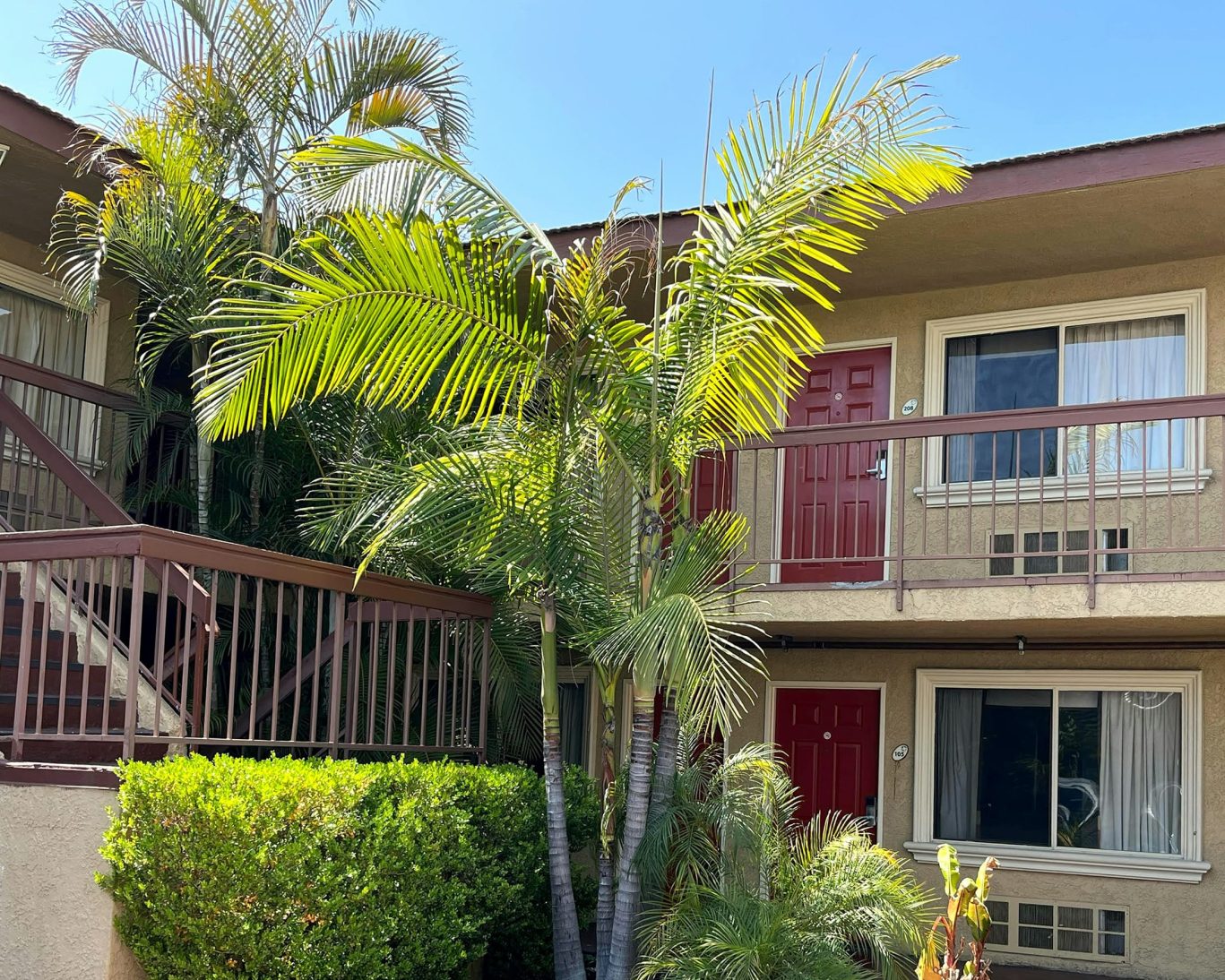 Upstairs and downstairs guest rooms with palm trees at Rivera Inn & Suites Motel.