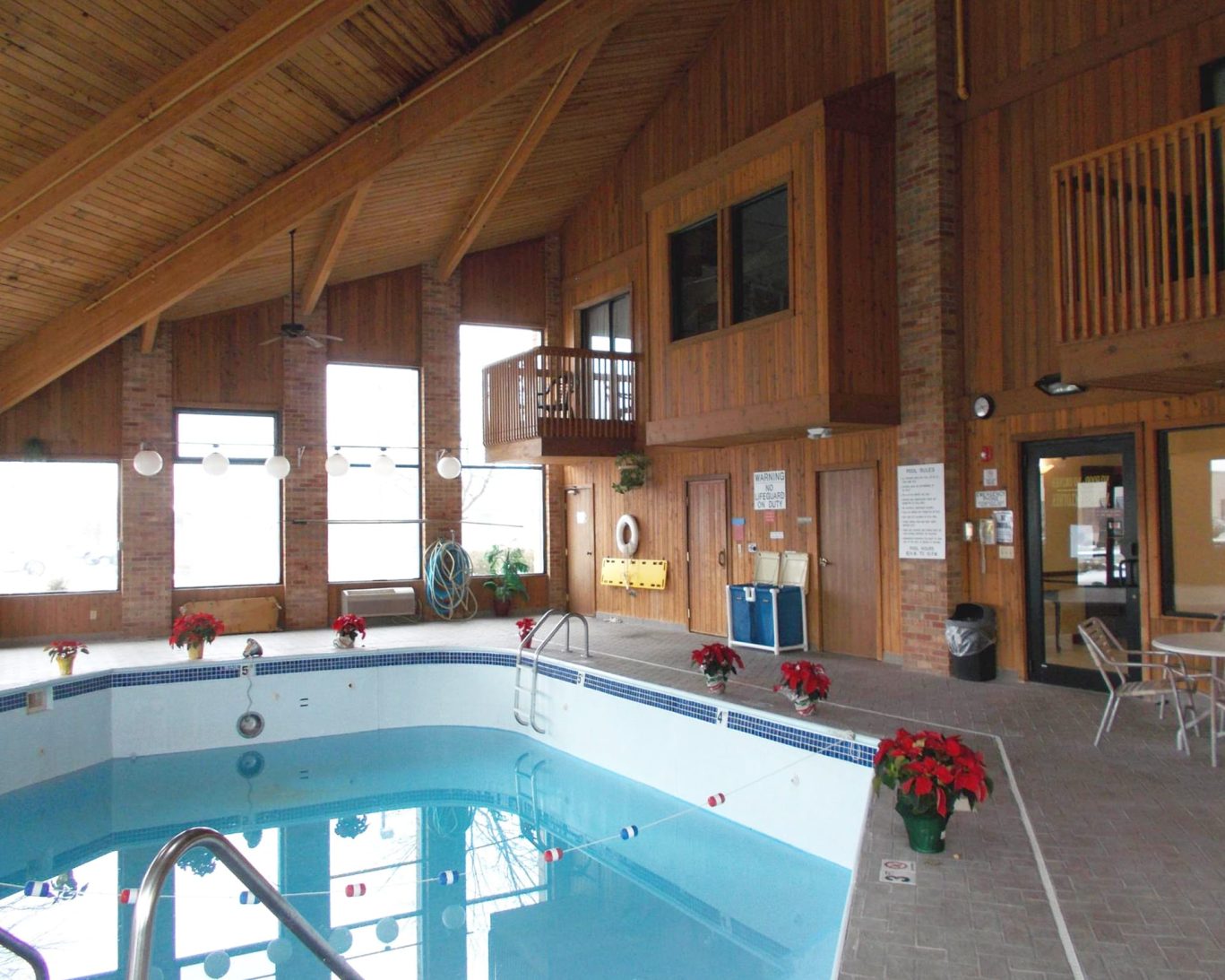 Spacious indoor pool at Royalton Inn & Suites Wilmington with wood-paneled interior and natural lighting.