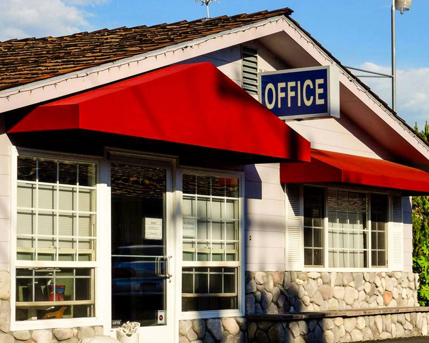 Ruby Inn Bridgeport front office with stone exterior and red awning under clear skies.