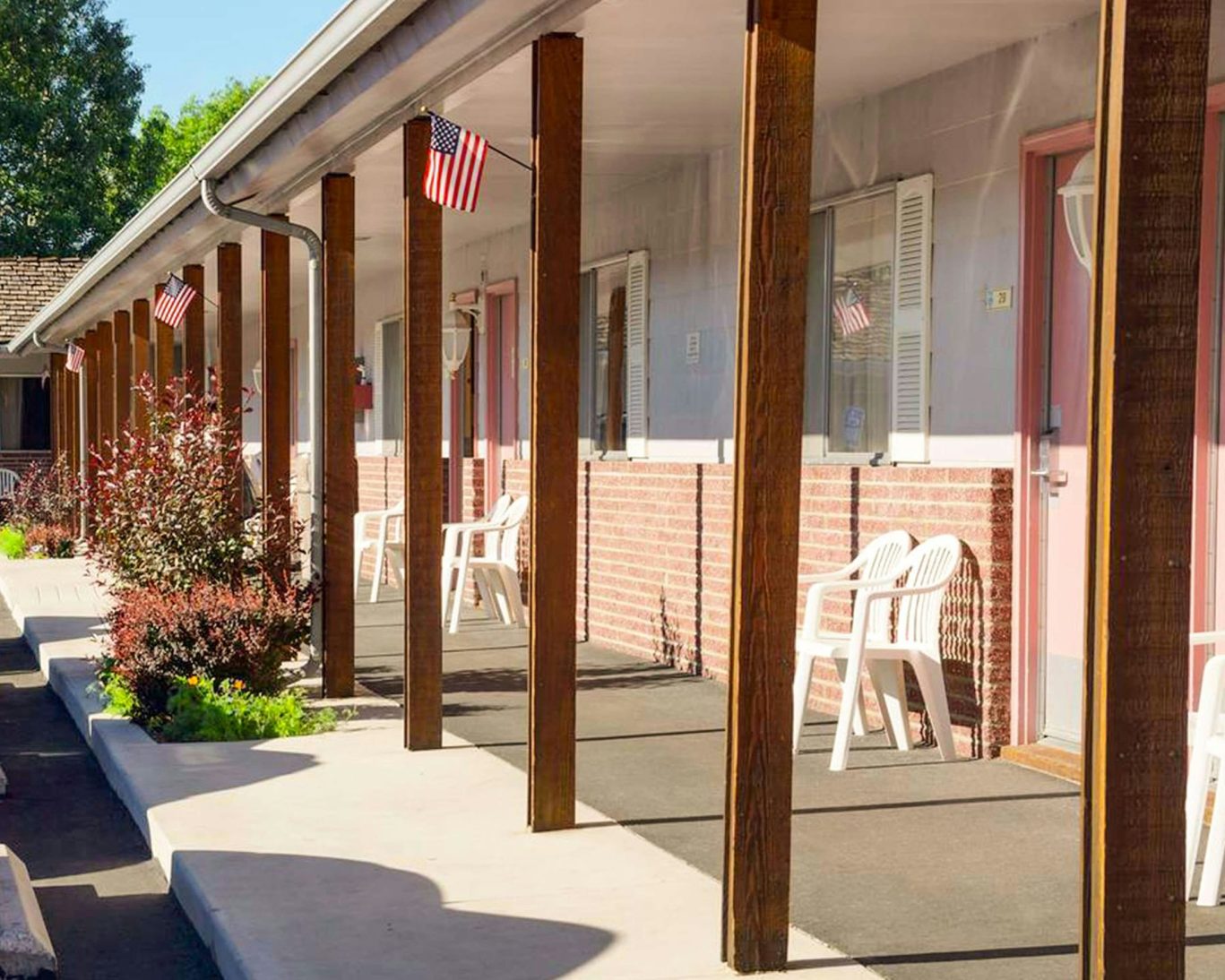 Exterior corridor at Ruby Inn Bridgeport with American flags and seating outside each guest room.
