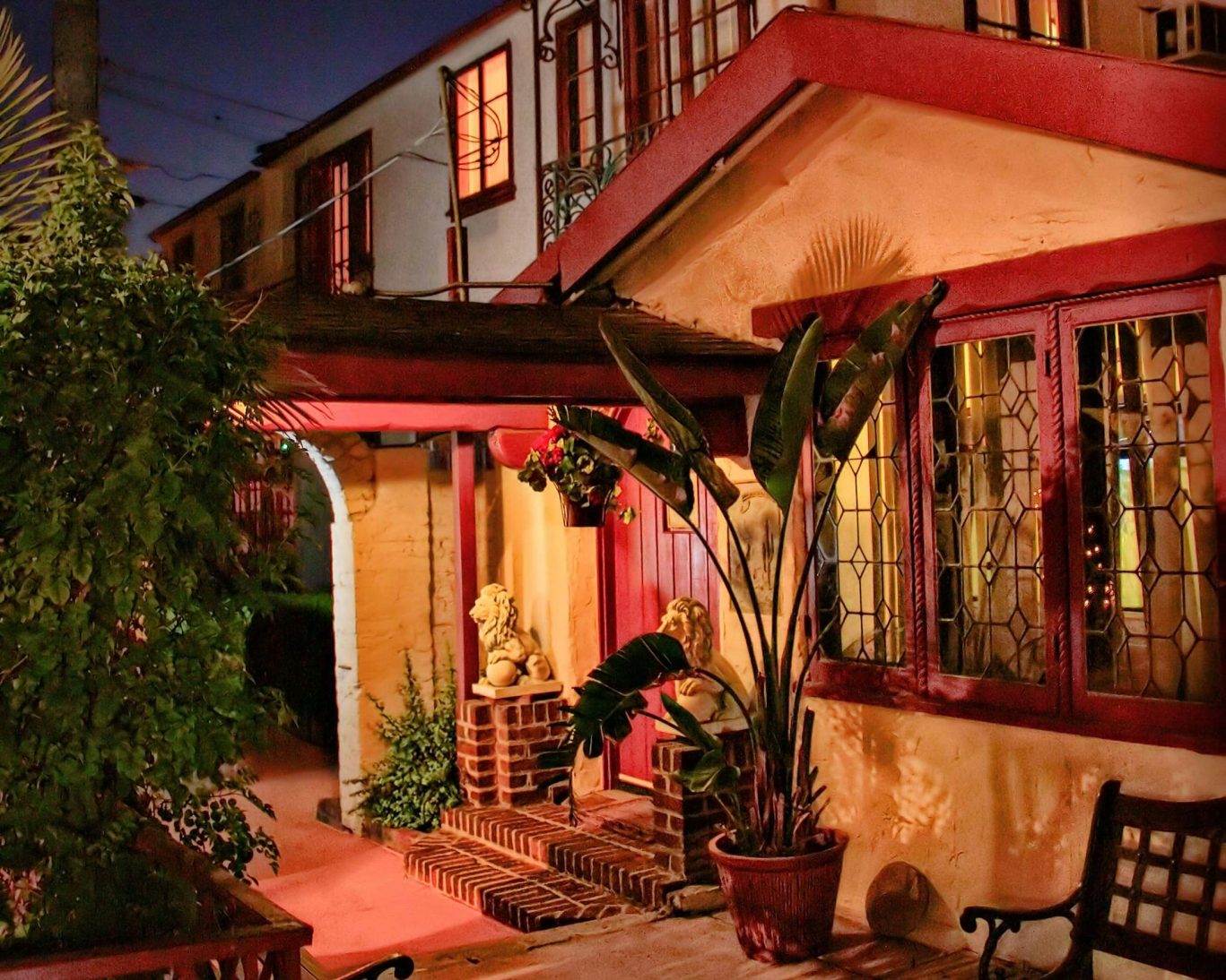 Charming Spanish-style courtyard at Santa Cruz Inn Riverside illuminated at night with tropical plants and lion statues.