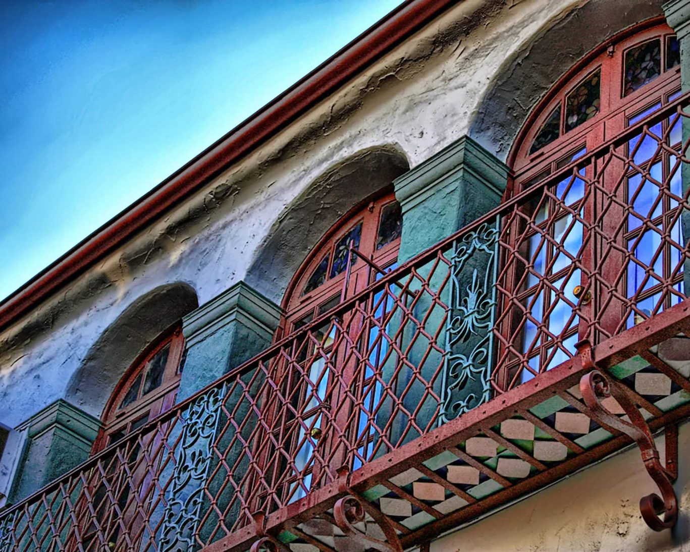 Decorative wrought iron balcony and arched windows on historic Santa Cruz Inn Riverside facade.