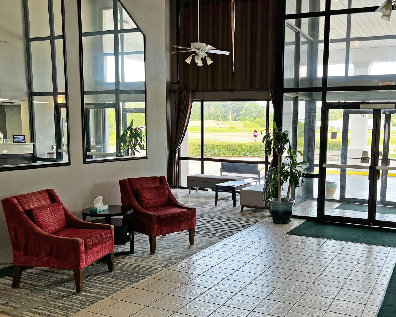 Spacious hotel lobby at Super Inn and Suites Philadelphia with natural light and red armchairs.