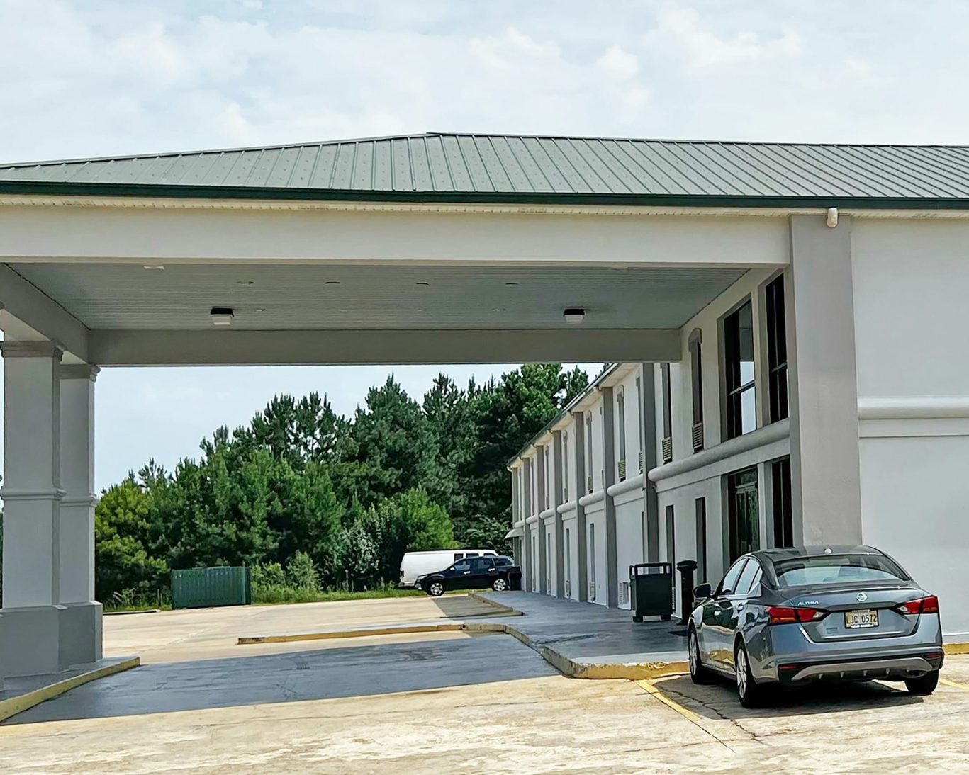 Drive-through canopy and guest parking at Super Inn and Suites Philadelphia surrounded by trees.