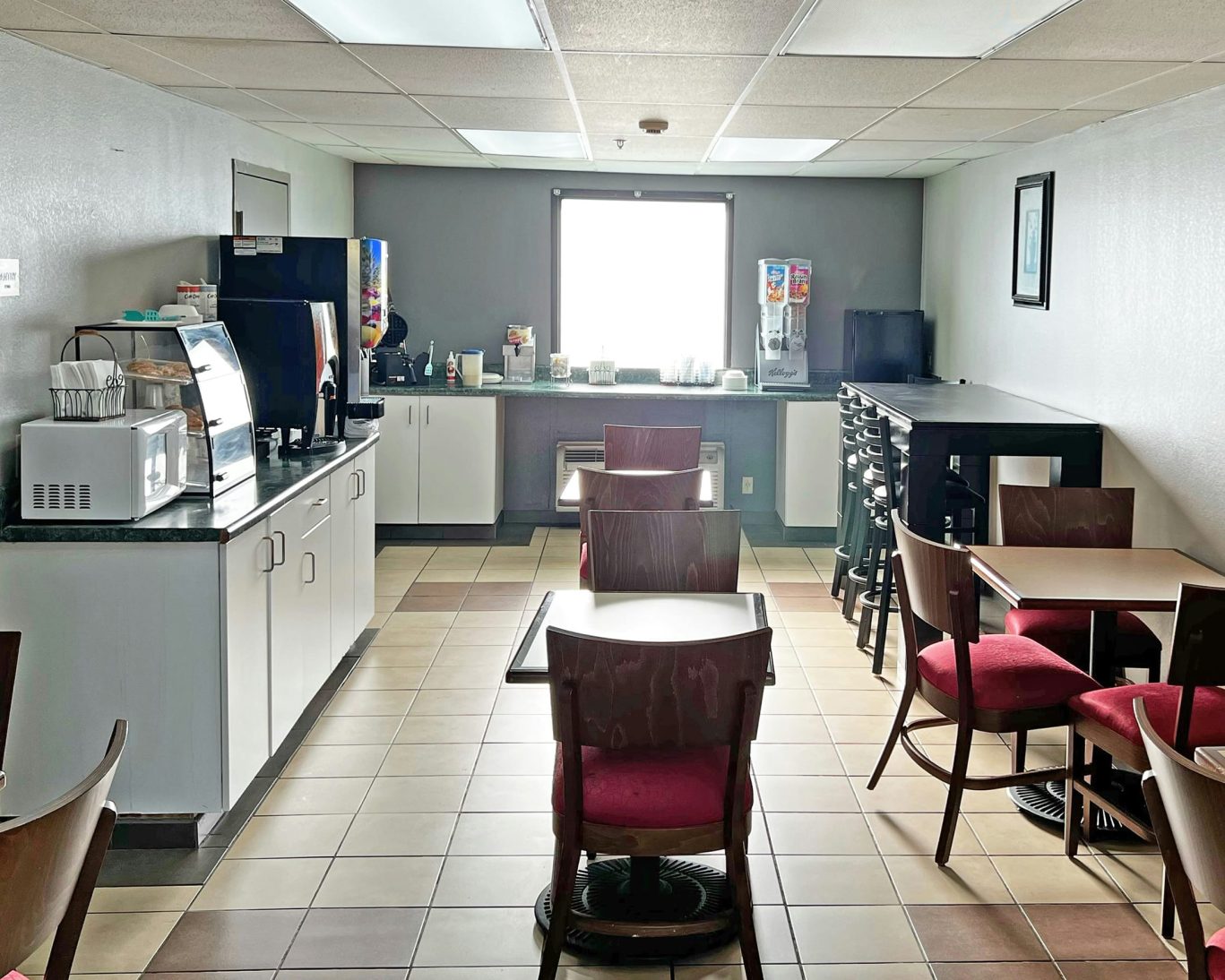 Casual breakfast area at Super Inn and Suites Philadelphia with coffee station, cereal, and dining tables.