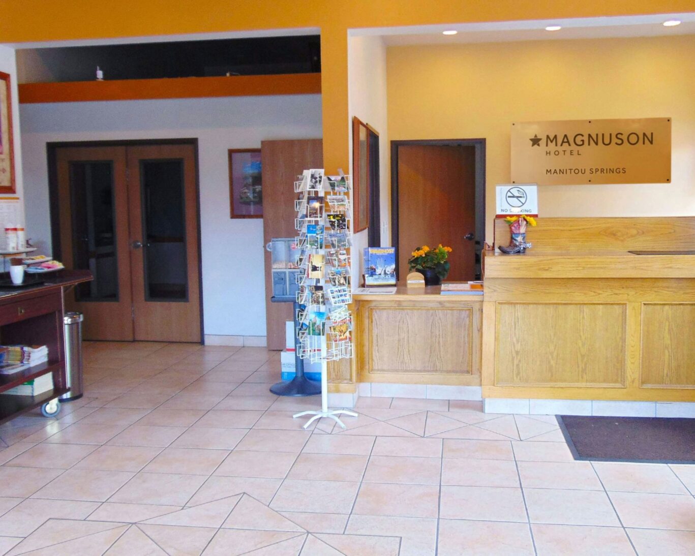 Tava Motel Manitou Springs front desk and reception area with postcard rack and tiled flooring.